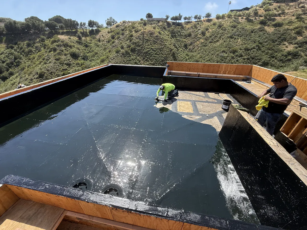 Two KCJ Contracting crew members on a completed below grade waterproofing membrane