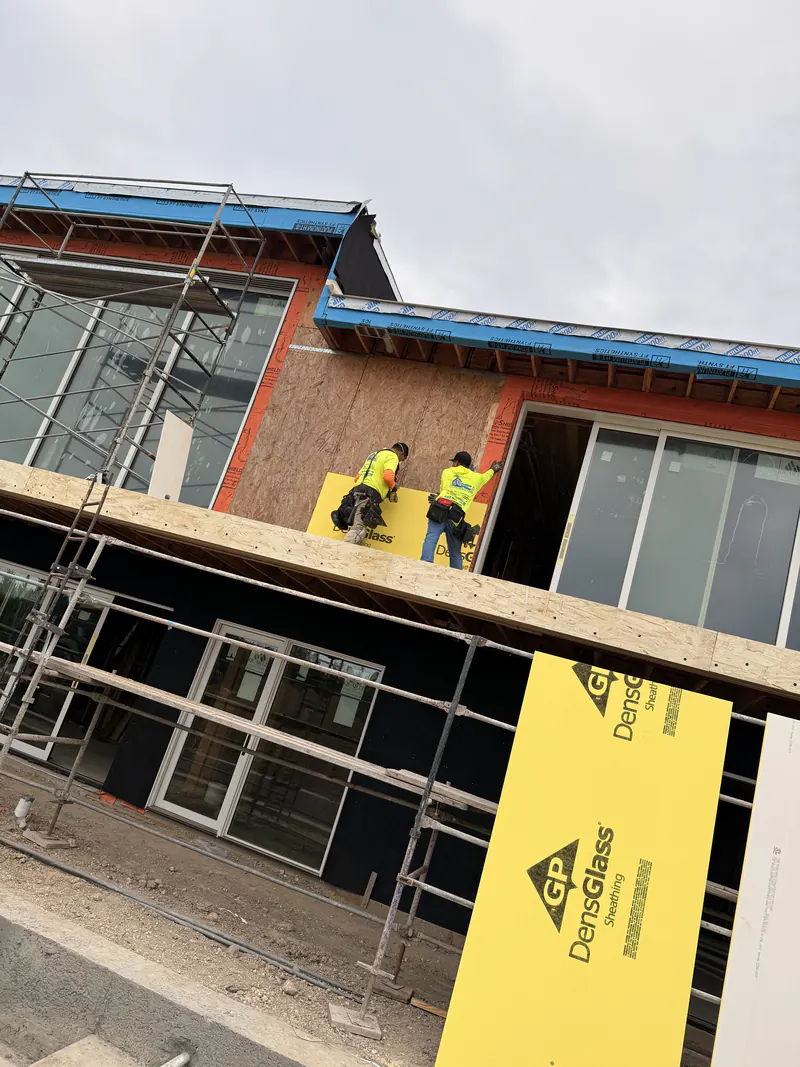 KCJ Contracting crew installing exterior sheathing from scaffolding on a custom home