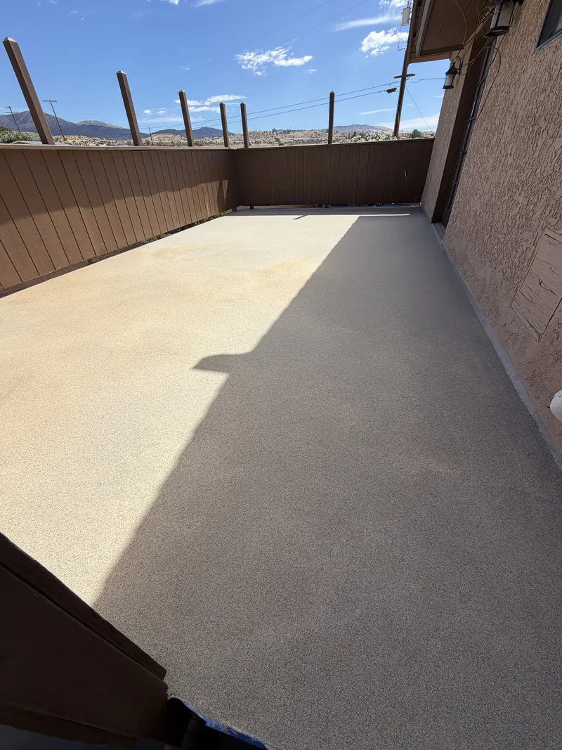 Finished textured deck coating over a roof deck, sealed to the building wall