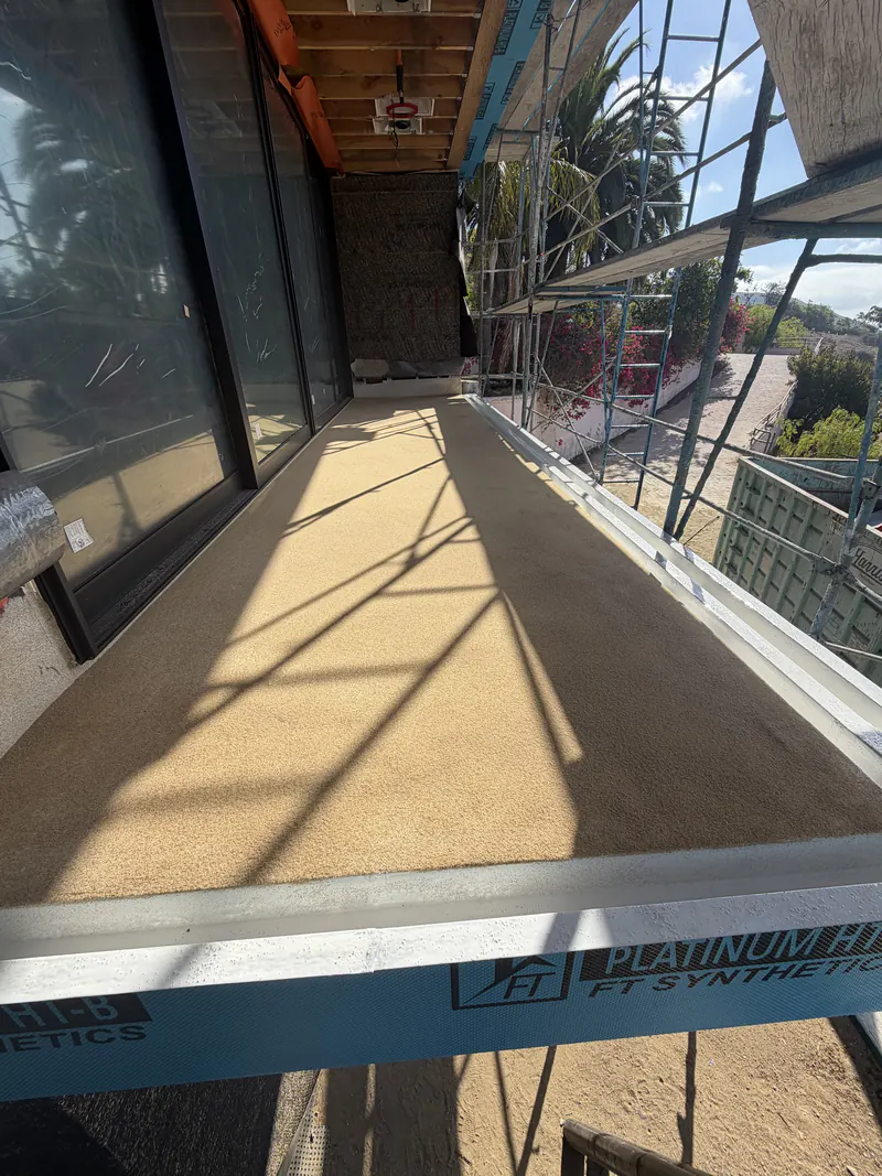 Finished waterproof deck coating on a balcony beside a glass wall with an ocean view
