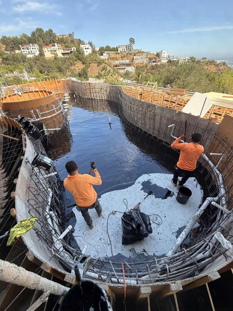 Two KCJ Contracting crew members checking a flood test on a below grade slab