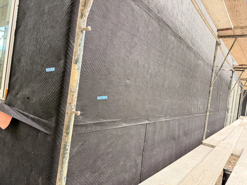Close detail of a lapped weather barrier membrane at a wall transition