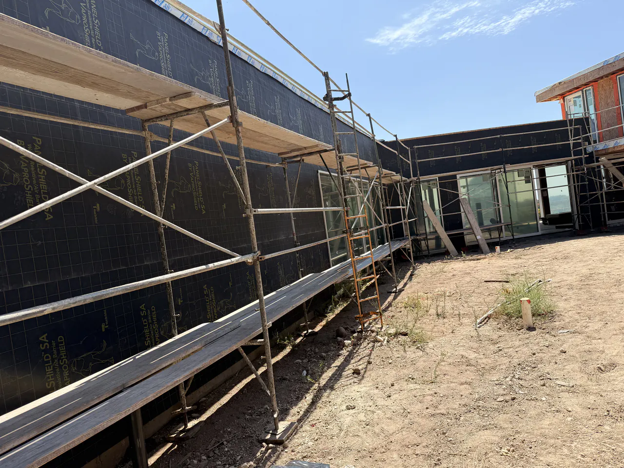 Weather resistive barrier installed on a Malibu residence with scaffolding and the Pacific behind